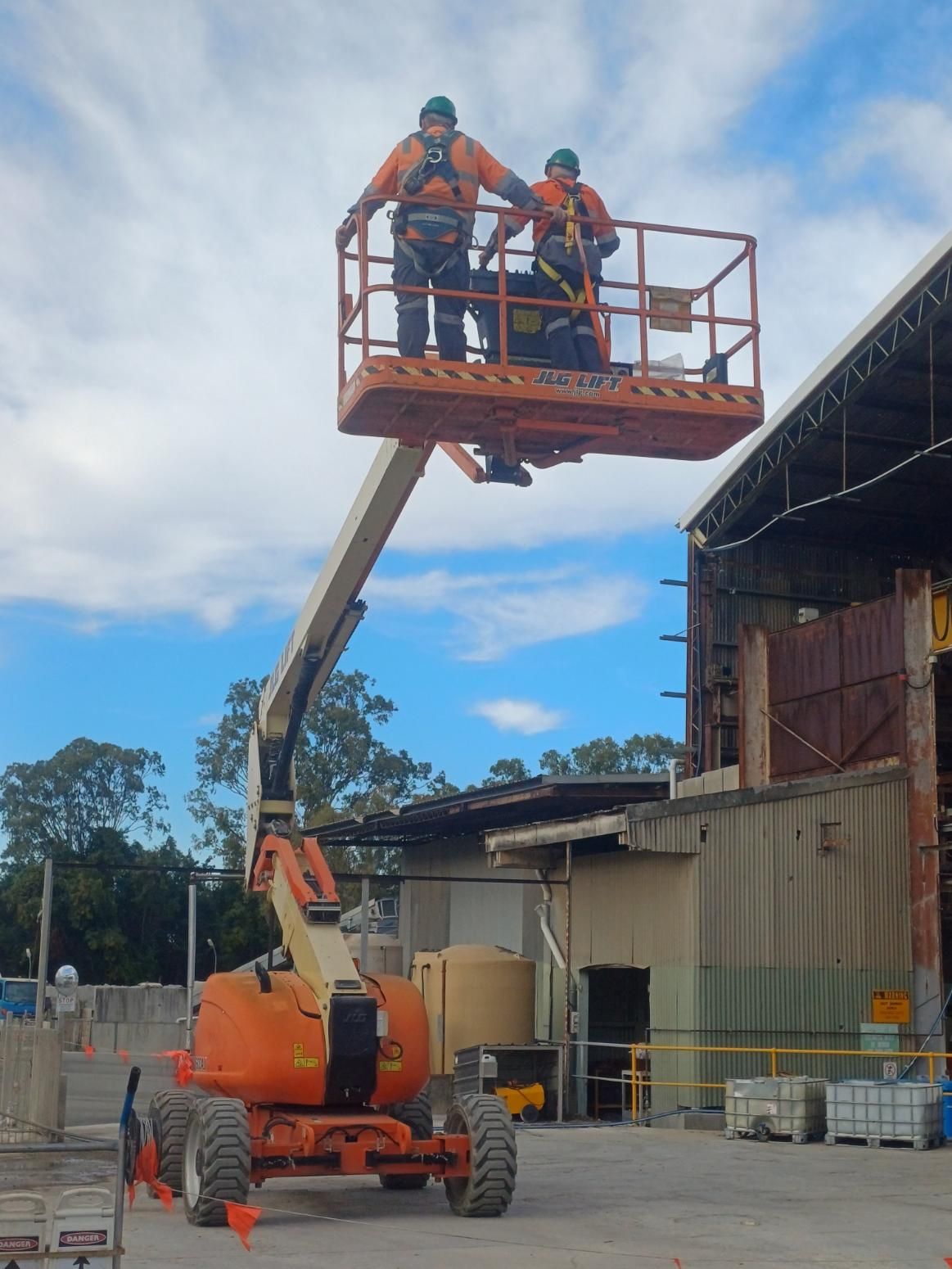 Two Men Are Standing on a Lift in Front of a Building — Advanced Industry Training In South Townsville, QLD