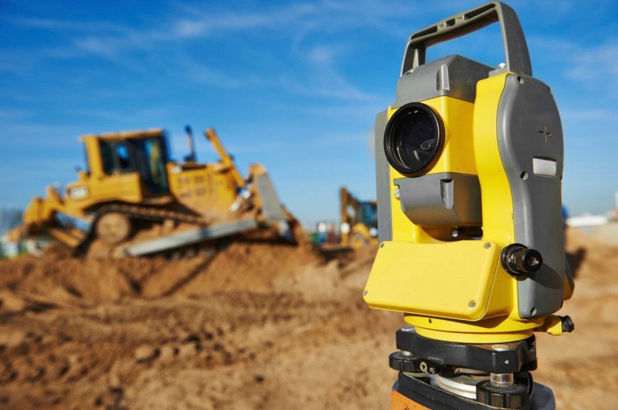 A Yellow Theodolite is Sitting in Front of a Bulldozer — Advanced Industry Training In South Townsville, QLD