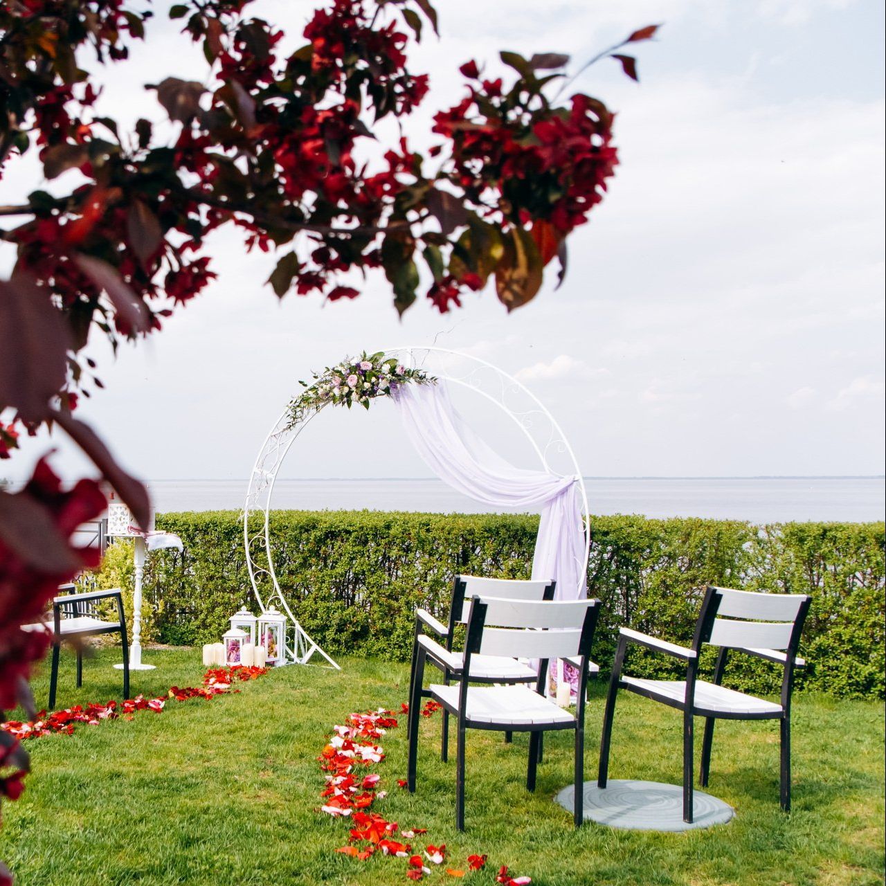 A wedding ceremony is taking place in the grass near the ocean.