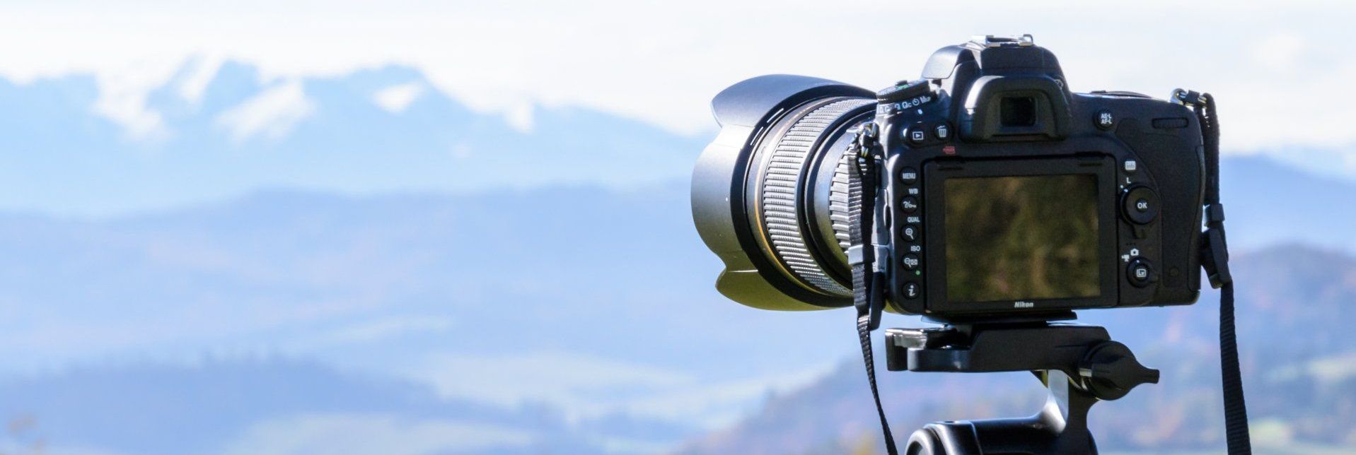 A camera is sitting on a tripod in front of a mountain range.