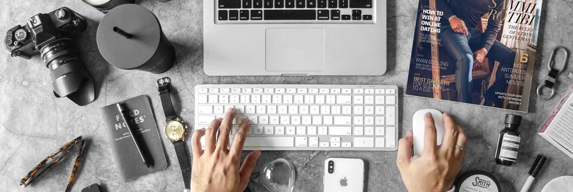A person is typing on a laptop computer with a mouse.