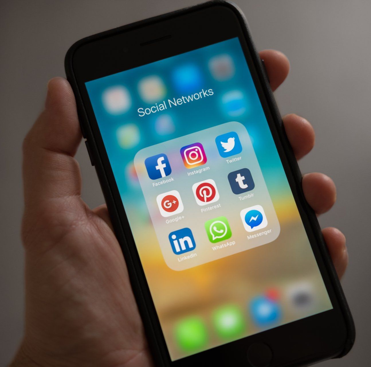 A person is holding a cell phone with social networks on the screen