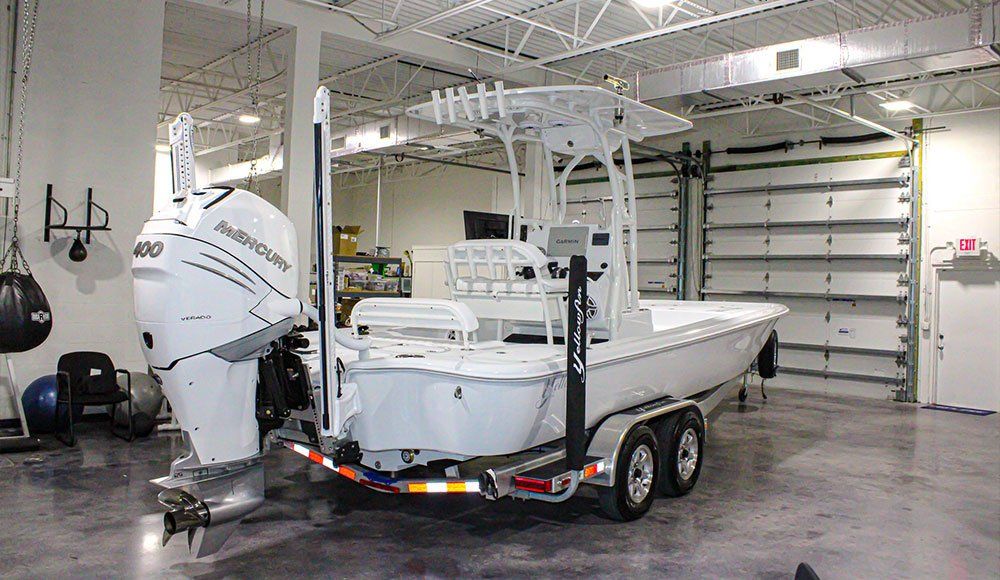 A white boat is sitting on a trailer in a garage.
