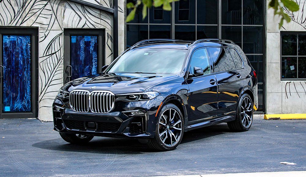 A black bmw x7 is parked in front of a building.