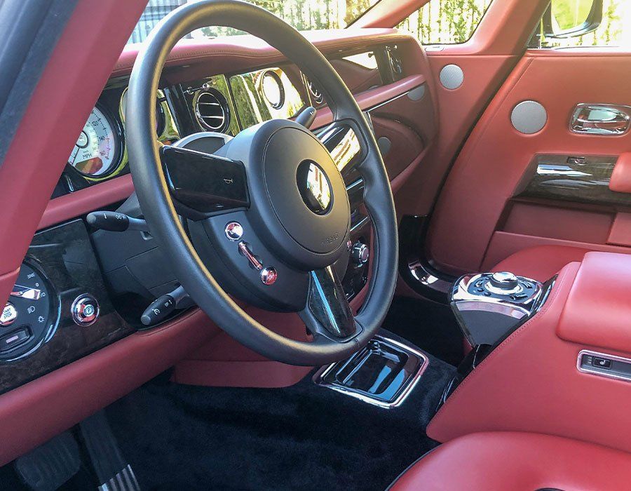 The inside of a car with red seats and a black steering wheel