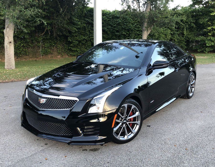 A black cadillac is parked on the side of the road.