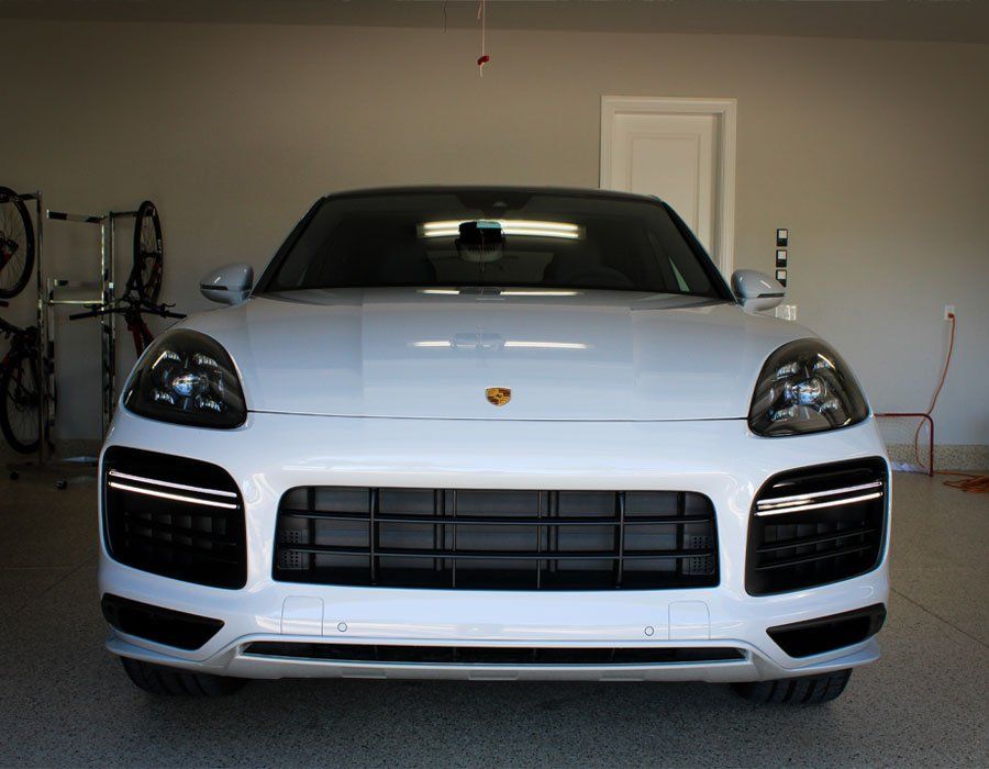 A white porsche cayenne is parked in a garage