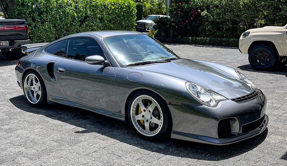 A gray porsche 911 turbo is parked in a parking lot.