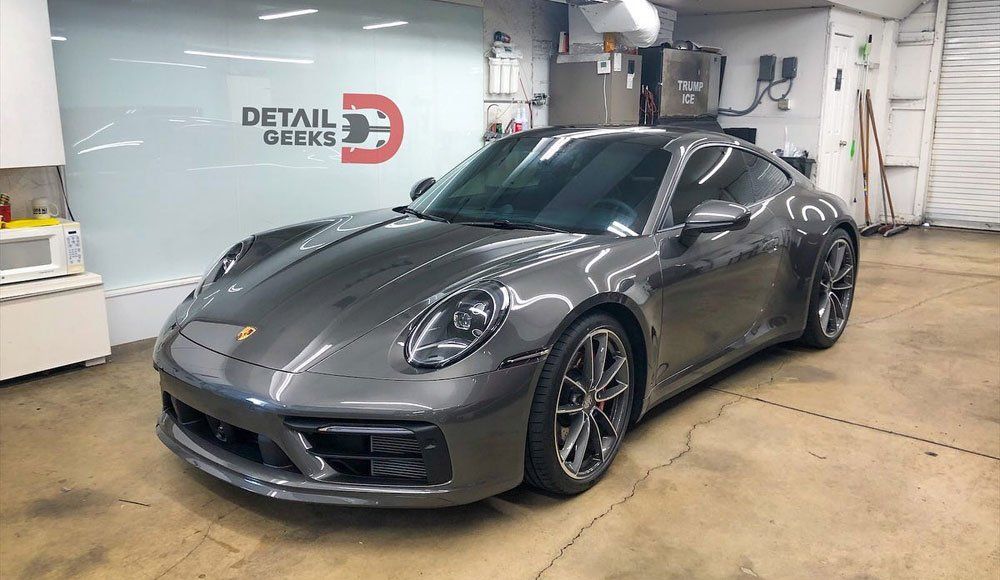 A gray porsche 911 is parked in a garage.