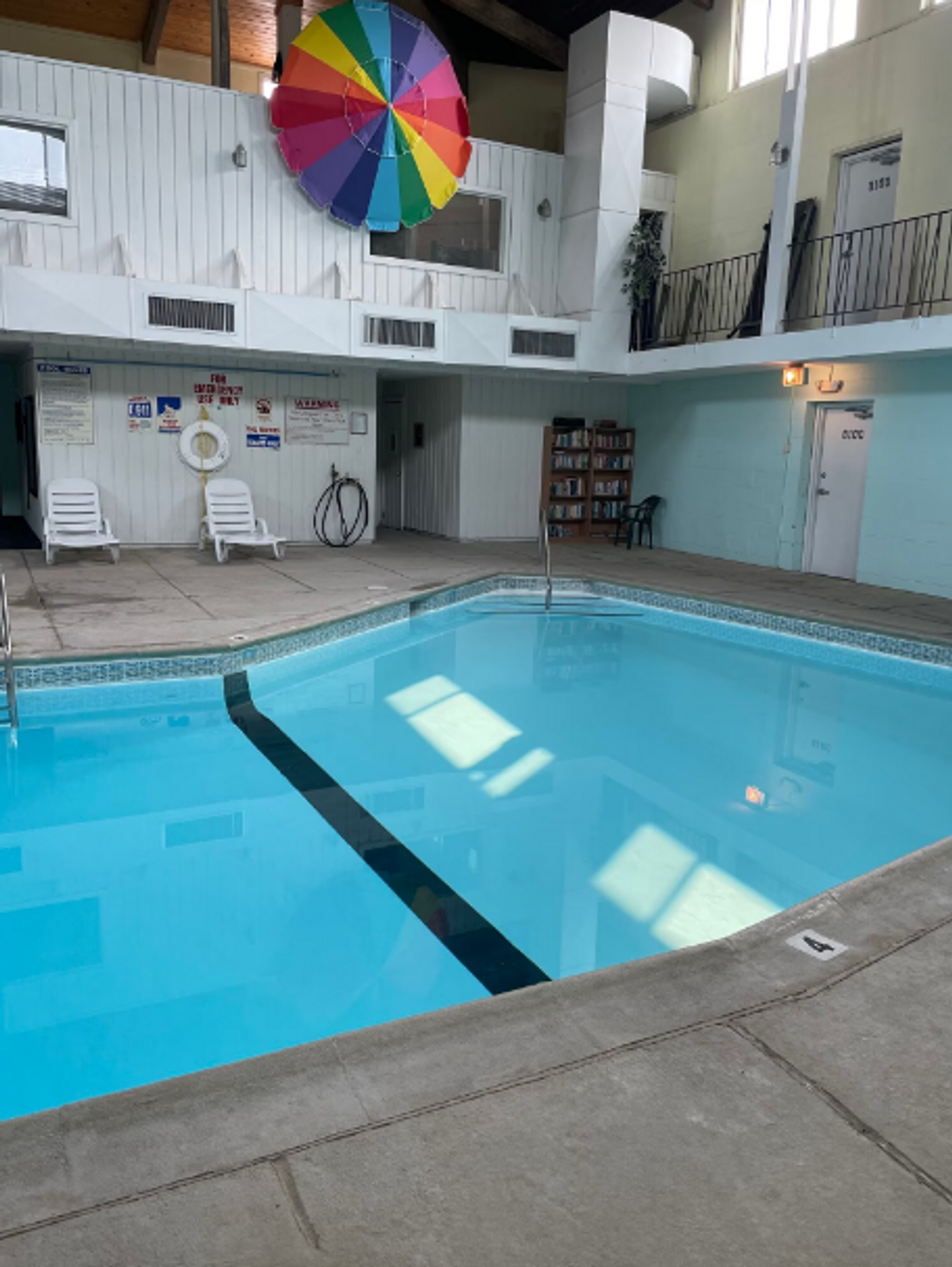 A large indoor swimming pool with a rainbow umbrella above it