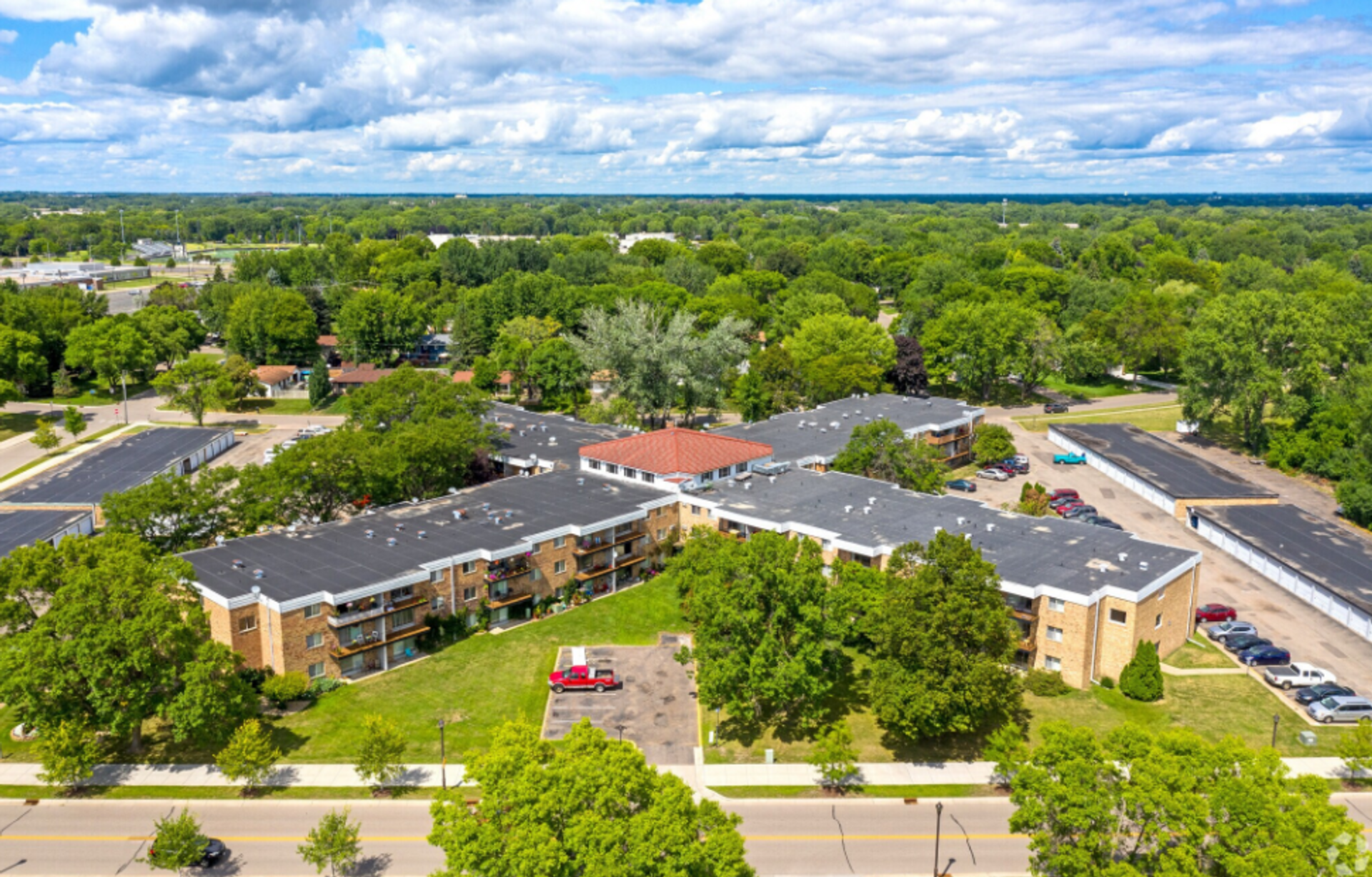 An aerial view of a large building surrounded by trees and a parking lot.