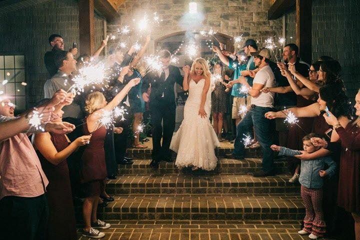 Wedding couple on steps beneath sparklers held by cheering guests at night