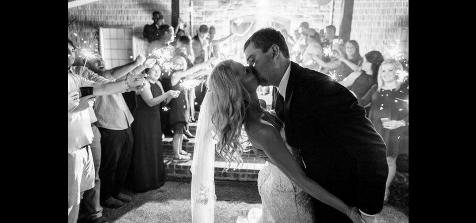 Bride and groom kiss during their wedding reception as guests clap around them