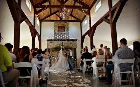 Wedding ceremony in a rustic chapel, with bride and guests seated in a bright timber-framed hall