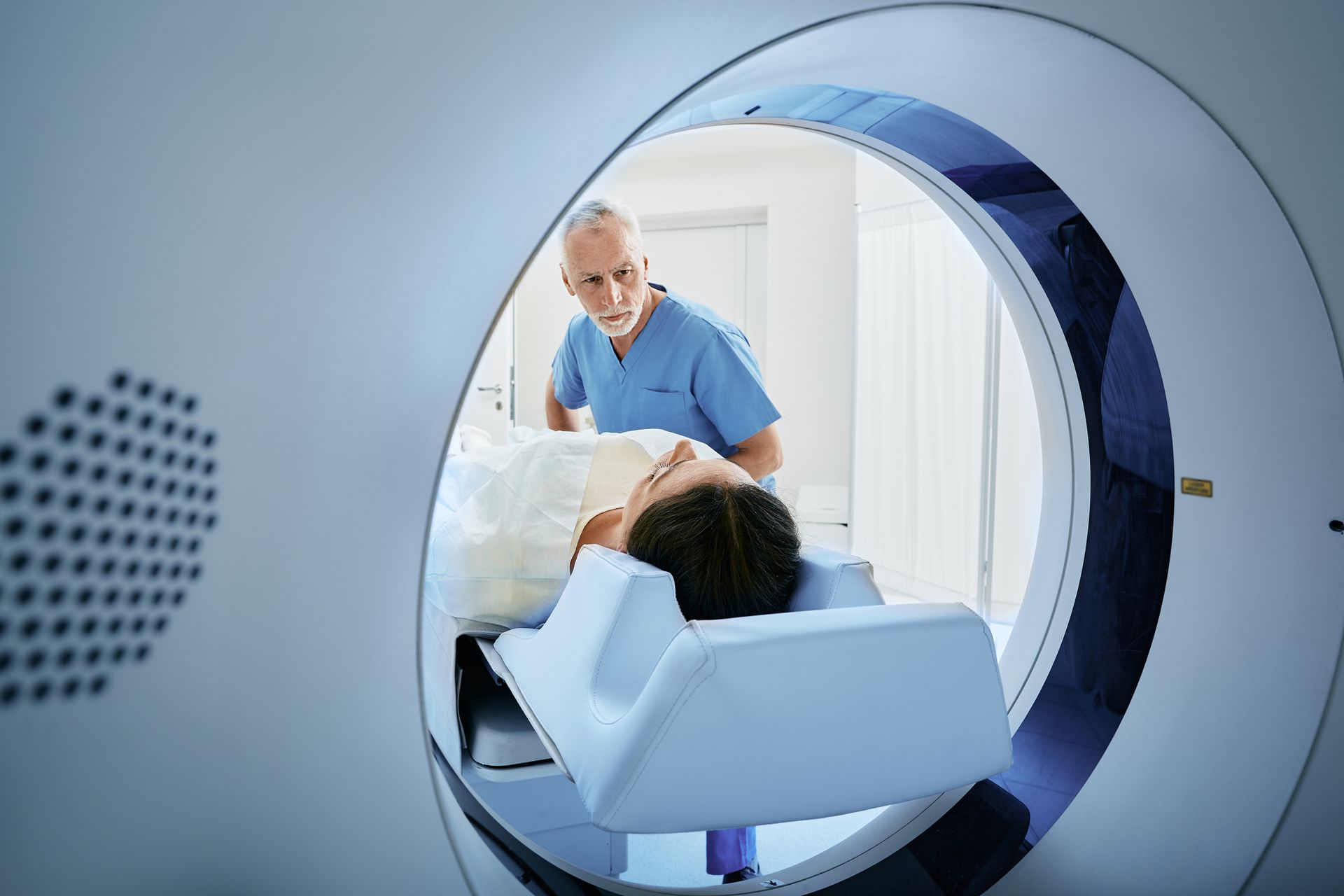 Una mujer está acostada en una cama de hospital haciéndose una tomografía computarizada.