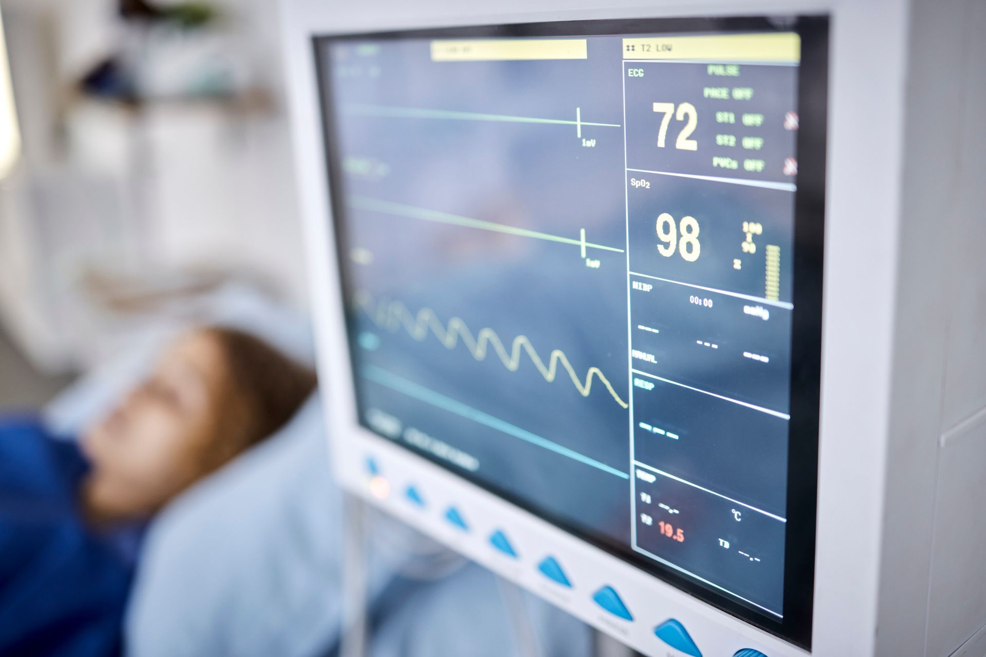 Una persona está acostada en una cama de hospital y un monitor muestra sus signos vitales.