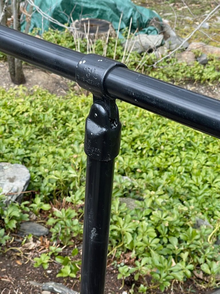 Black metal railing joint beside green ground cover and rocks