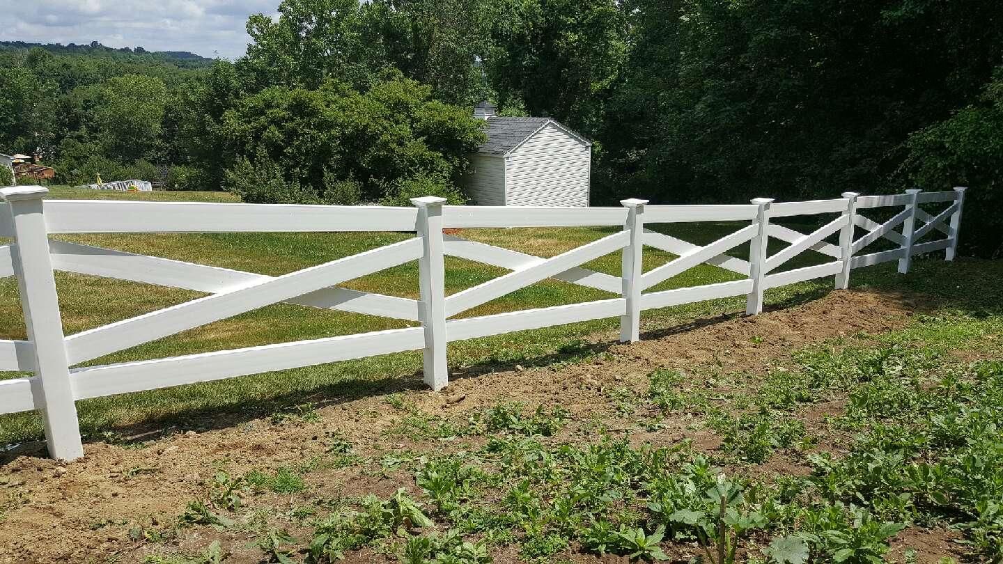 White wooden fence in a grassy yard with a small white lattice trellis in the background