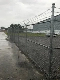 Wet chain-link fence along an industrial lot on a rainy day