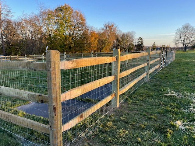 Wooden fenced pasture beside a grassy path at sunset