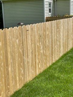 Wooden privacy fence beside a green lawn, with a house in the background.