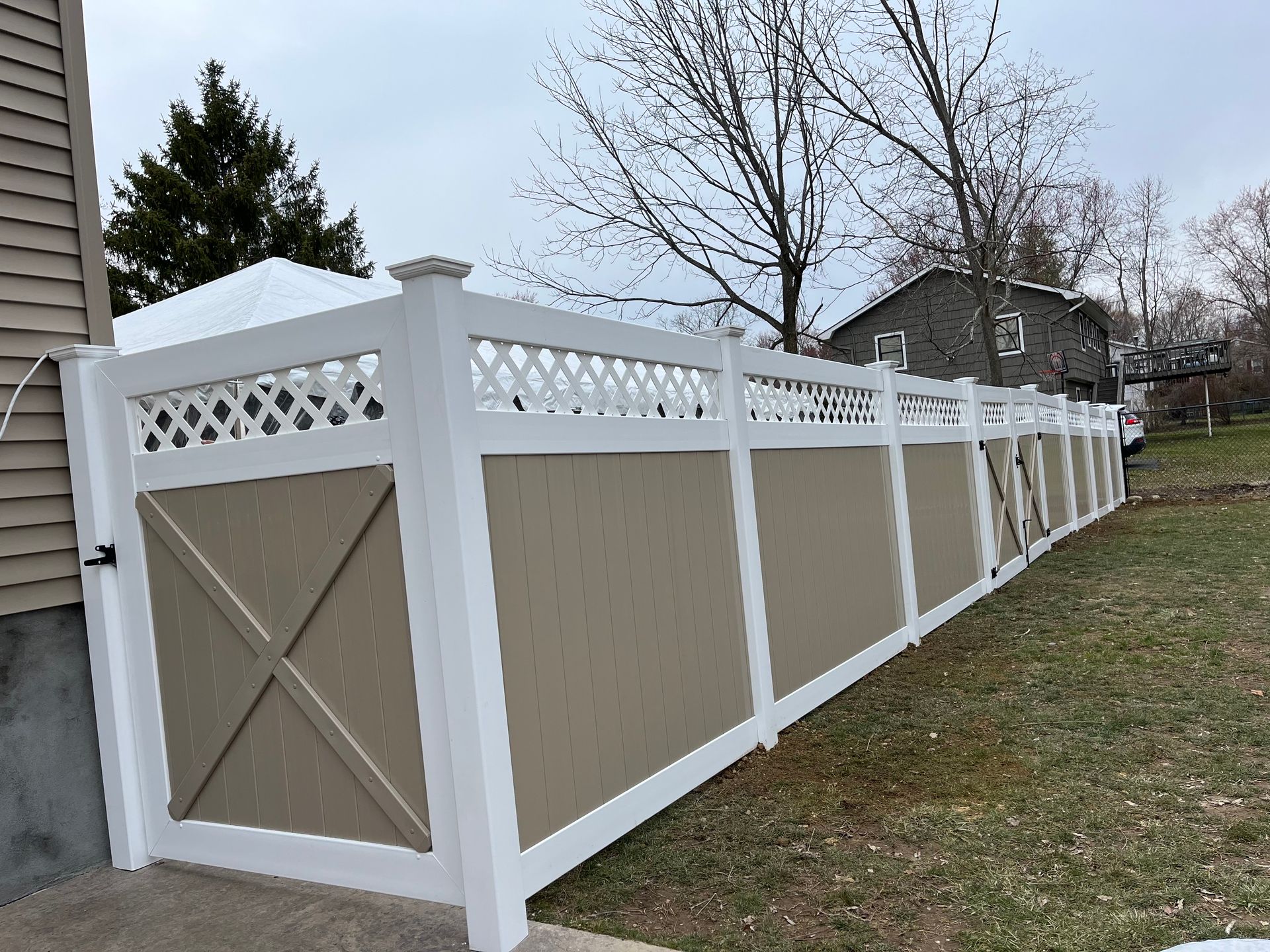 White privacy fence with tan panels and lattice top along a sloped backyard