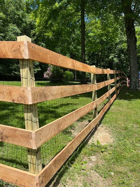 Wooden post-and-rail fence along a grassy path in a wooded area