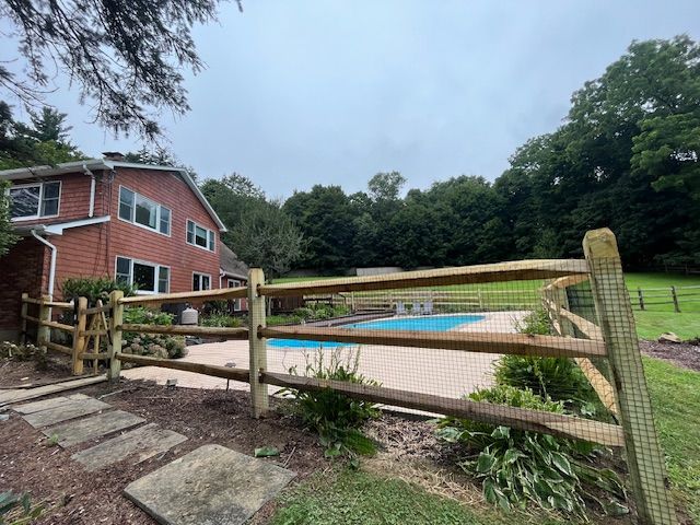 Brick house with fenced swimming pool and wooden deck in a leafy backyard