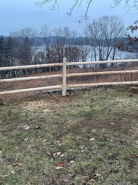 Wooden fence overlooking a wintery lake and bare trees under a gray sky