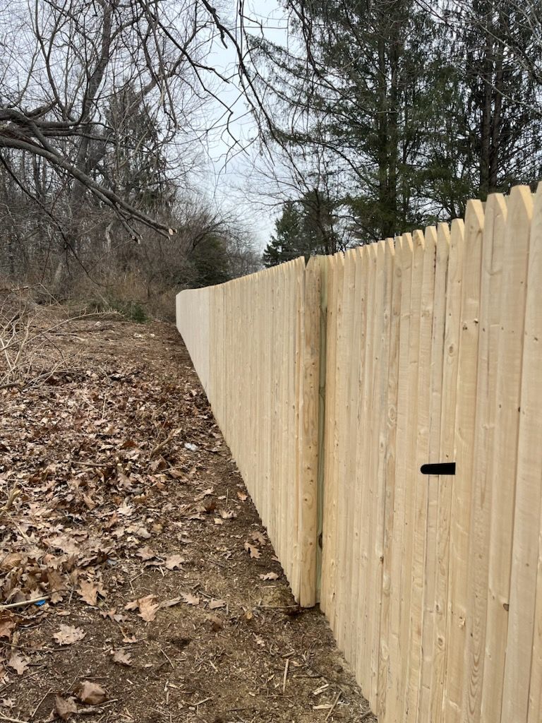 Wooden fence along a leaf-covered path in a wooded area