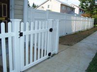 White picket fence lining a sidewalk beside suburban houses and a driveway