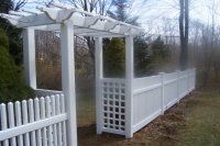 White wooden fence and arbor-style gate along a wooded path in winter