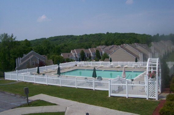 Outdoor swimming pool with white fence and lounge chairs in a residential complex