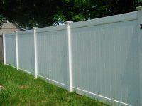 White vinyl privacy fence along a grassy yard under trees
