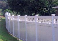 White vinyl privacy fence along a grassy yard with trees in the background