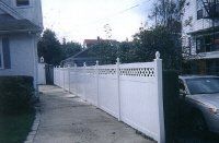 White fence lining a sidewalk beside a parked car in a residential street at dusk