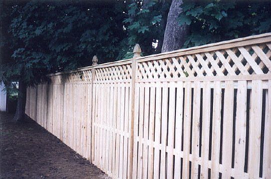 Long white wooden fence along a tree-lined path at dusk