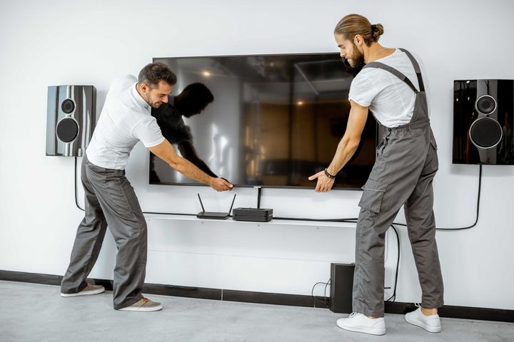 two men are installing a flat screen tv on a wall
