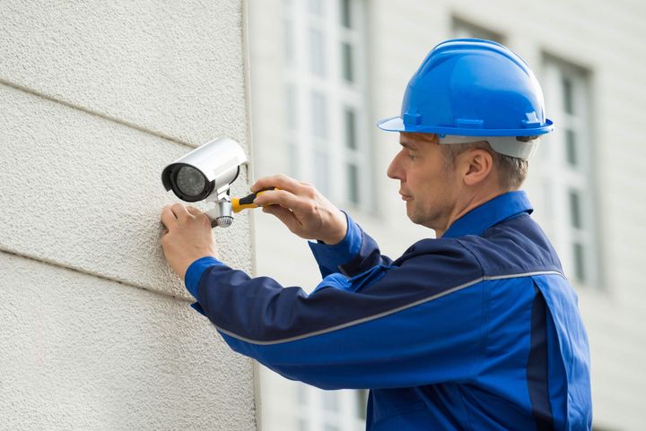a man is installing a security camera on the side of a building