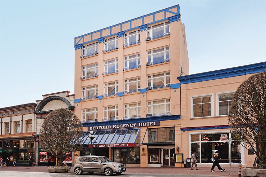 A large building with a lot of windows is located on a city street.