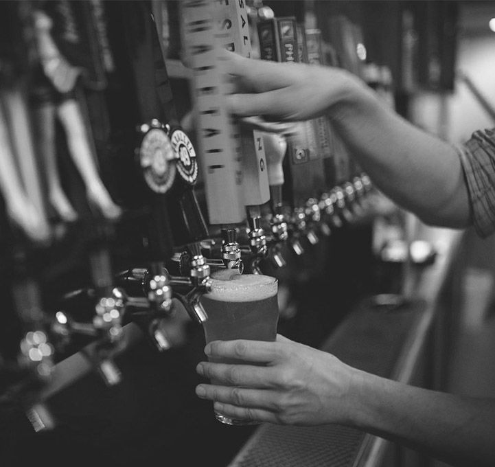 A person is pouring beer into a glass at a bar.