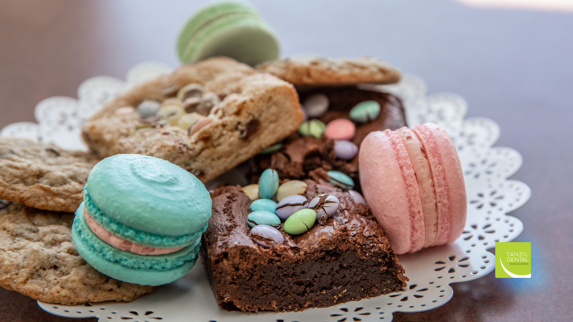 A plate of cookies , macarons , brownies and other desserts on a table.