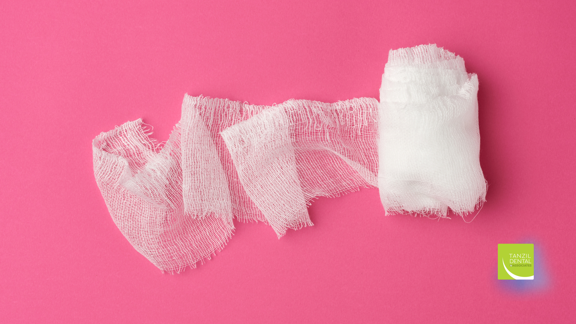 White gauze bandage unrolled on a pink background.
