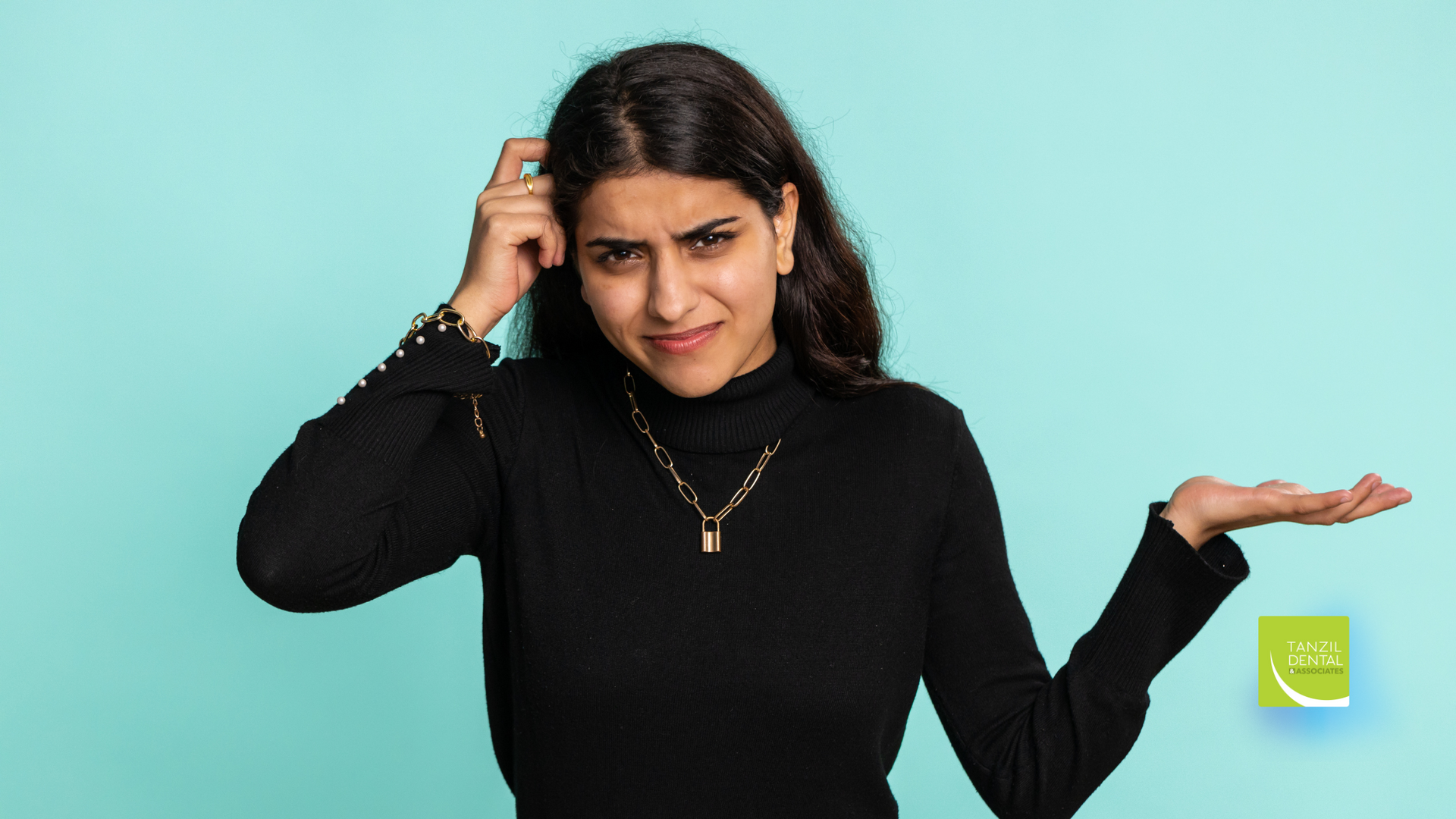 A woman in a black sweater is scratching her head and shrugging her shoulders.