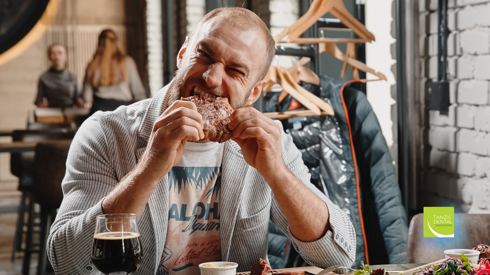 A man is sitting at a table in a restaurant eating a hamburger.