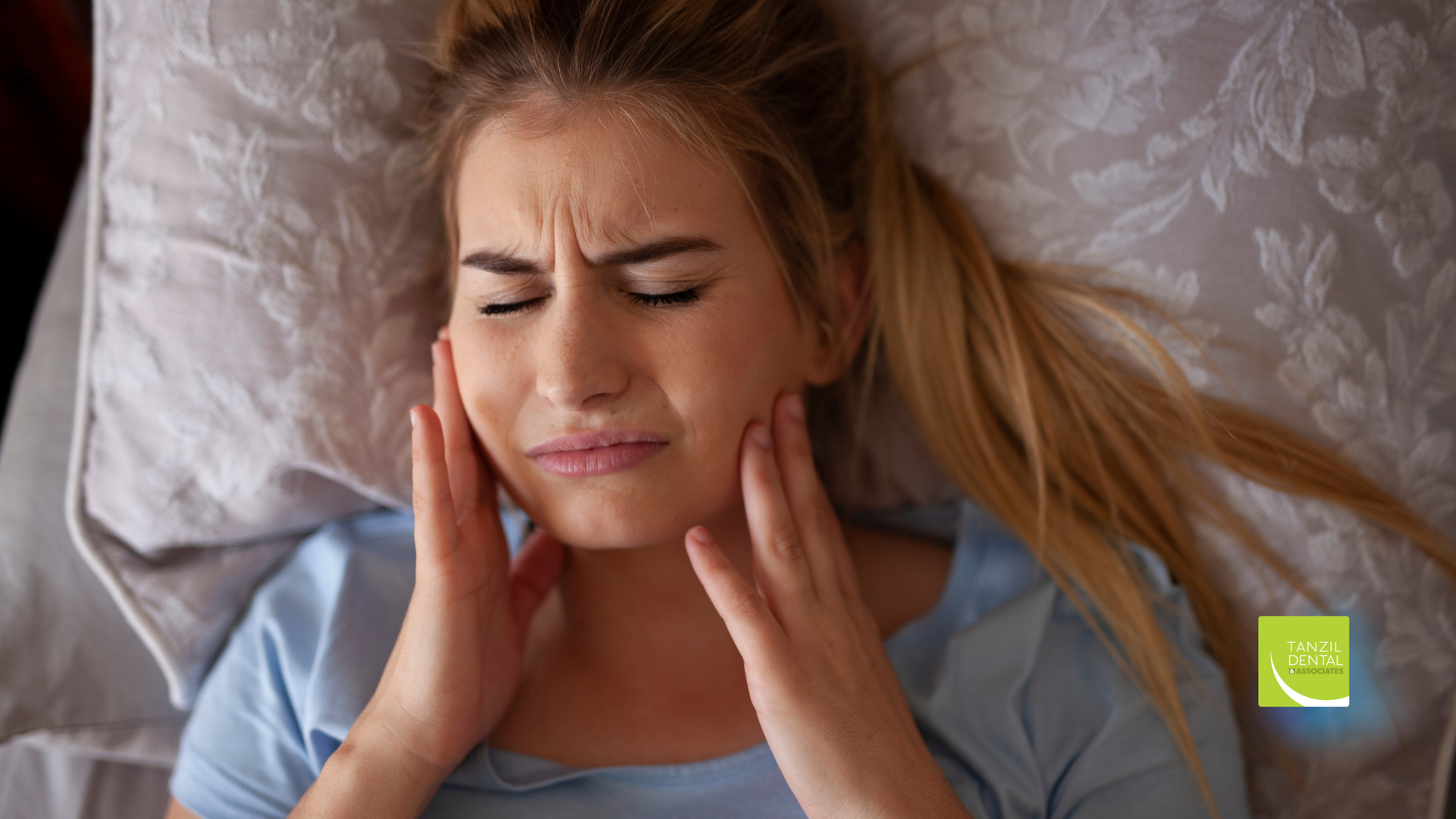 A woman is laying in bed with a toothache.