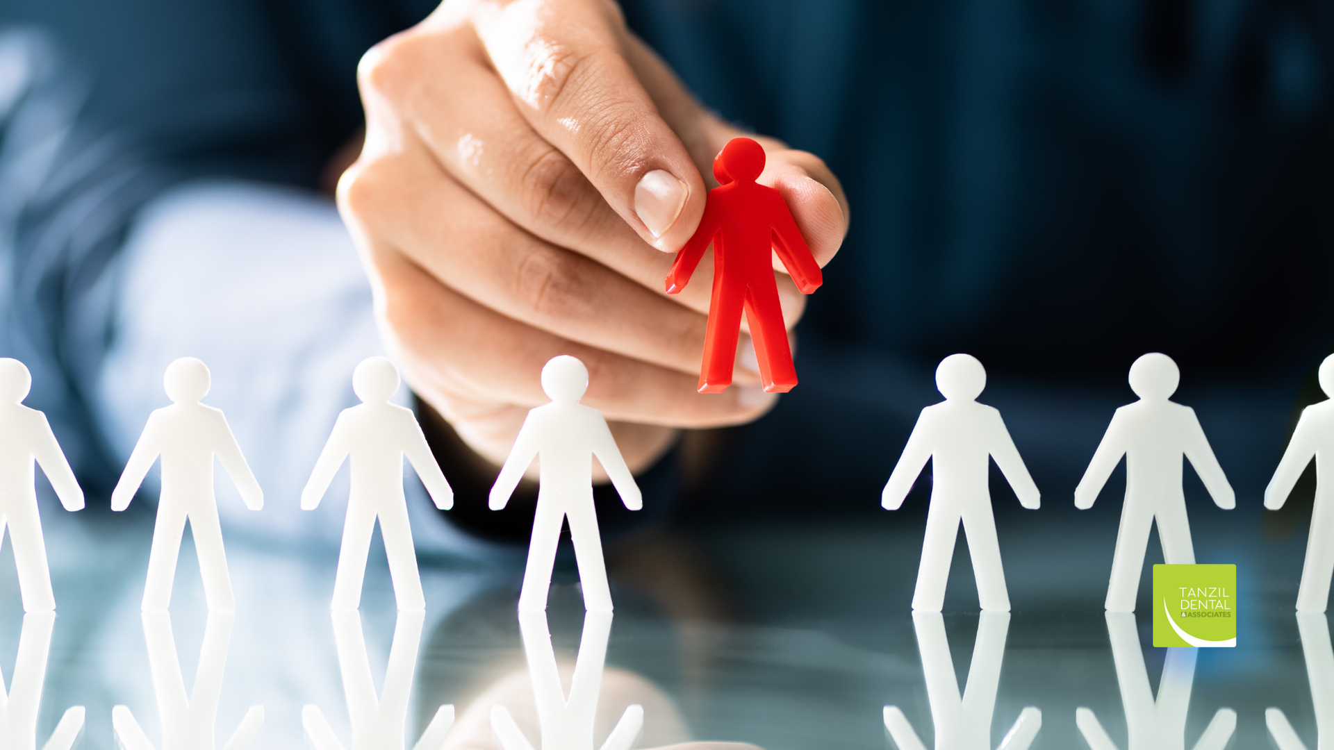 Hand selecting a red figure from a line of white figures, symbolizing recruitment or choice.