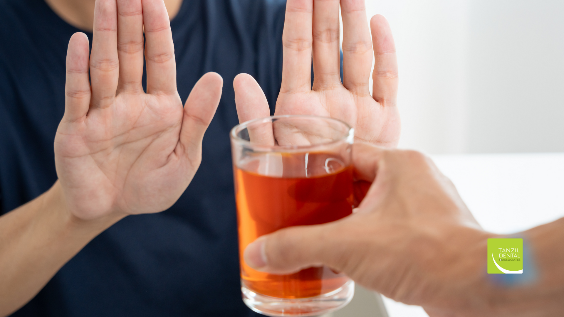 A man is refusing a glass of orange juice.