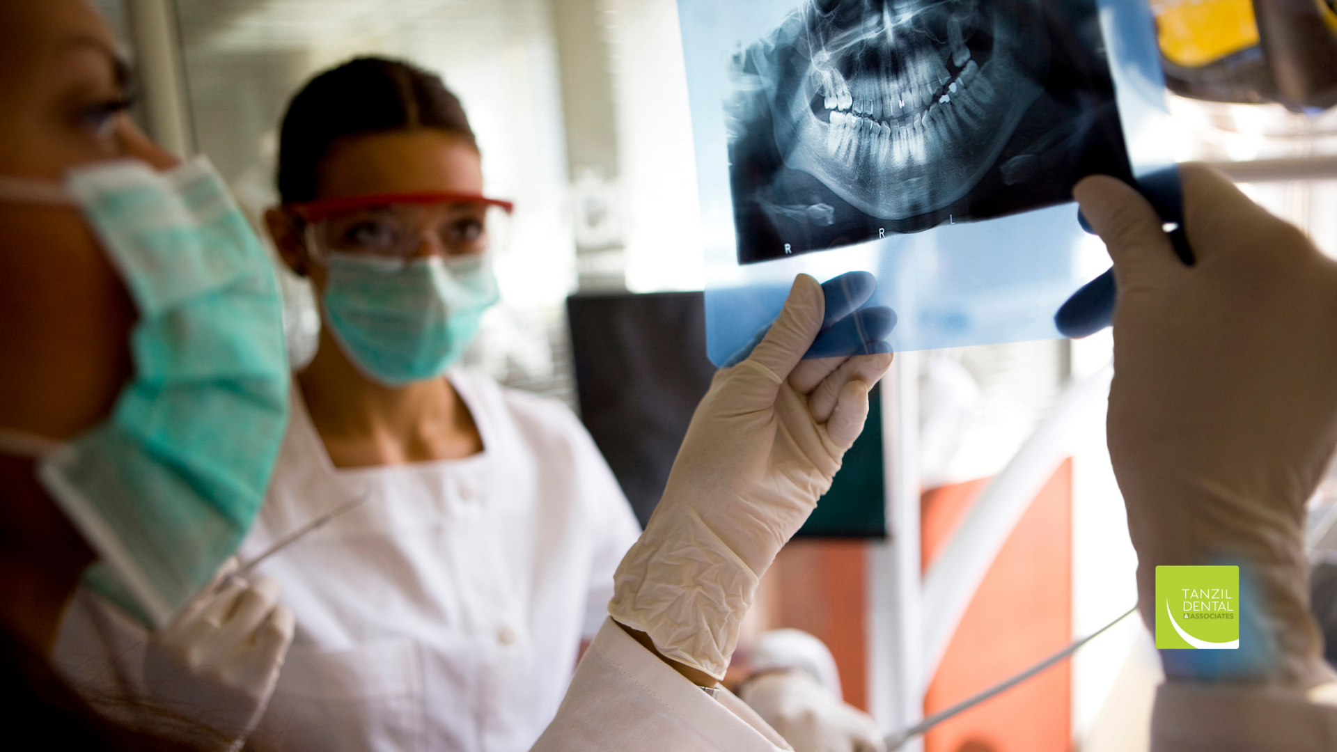 A dentist is looking at an x-ray of a patient 's teeth.
