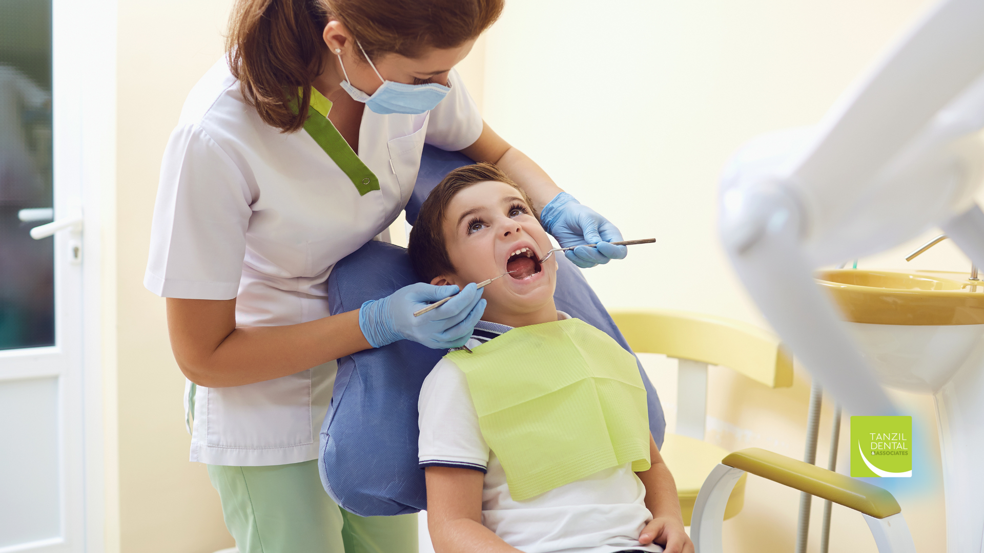 A young boy is sitting in a dental chair while a dentist examines his teeth.